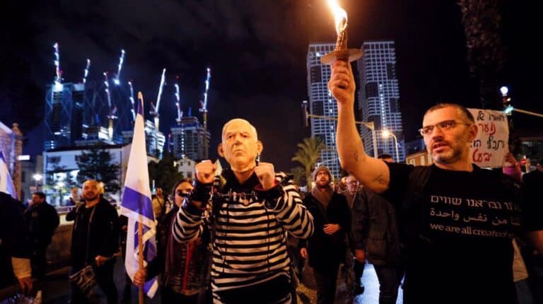 A man wears handcuffs and a mask depicting Israeli prime minister Benjamin Netanyahu, as he takes part in a protest against Netanyahu's new right-wing cabinet and its proposed judicial reforms in Tel Aviv, the occupied territories, on January 14, 2023. Photo: Reuters.