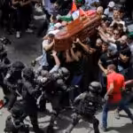 The mourning crowd carries the coffin of Shireen Abu Akleh while being attacked by police. Photo: Ammar Awad/Reuters.