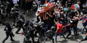The mourning crowd carries the coffin of Shireen Abu Akleh while being attacked by police. Photo: Ammar Awad/Reuters.