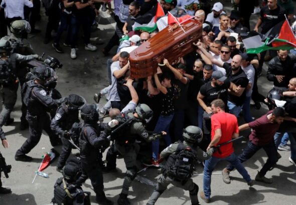 The mourning crowd carries the coffin of Shireen Abu Akleh while being attacked by police. Photo: Ammar Awad/Reuters.
