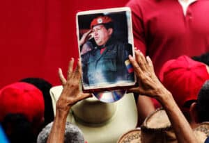 A person holds up a portrait of the late Hugo Chávez, Venezuela's president from 1999 to until his death in 2013, at a March 2019 demonstration. Photo: Ariana Cubillos/Associated Press.
