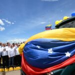 Several politicians stand by a Venezuelan flag billowing in the air. Photo: DEJÁLOME PENSAR.