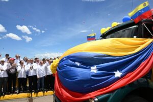 Several politicians stand by a Venezuelan flag billowing in the air. Photo: DEJÁLOME PENSAR.