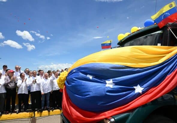 Several politicians stand by a Venezuelan flag billowing in the air. Photo: DEJÁLOME PENSAR.