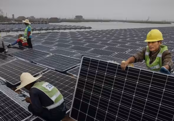 Chinese workers prepare panels that will be part of a large floating solar farm project under construction by the Sungrow Power Supply Company on a lake caused by a collapsed and flooded coal mine on June 13, 2017 in Huainan, Anhui province, China. Photo: Kevin Frayer/Getty Images.