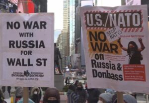 Antiwar protest in New York City and a close up to two banners. The first on the left reads "No war with Russia for Wall Street" and the second (right) reads "U.S./NATO, No war on Russia & Donbass, Stop NATO, Disband NATO now." Photo: Struggle La Lucha.