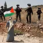 Woman waves Palestinian flag at IDF soldiers. Photo: Daily Sabah.