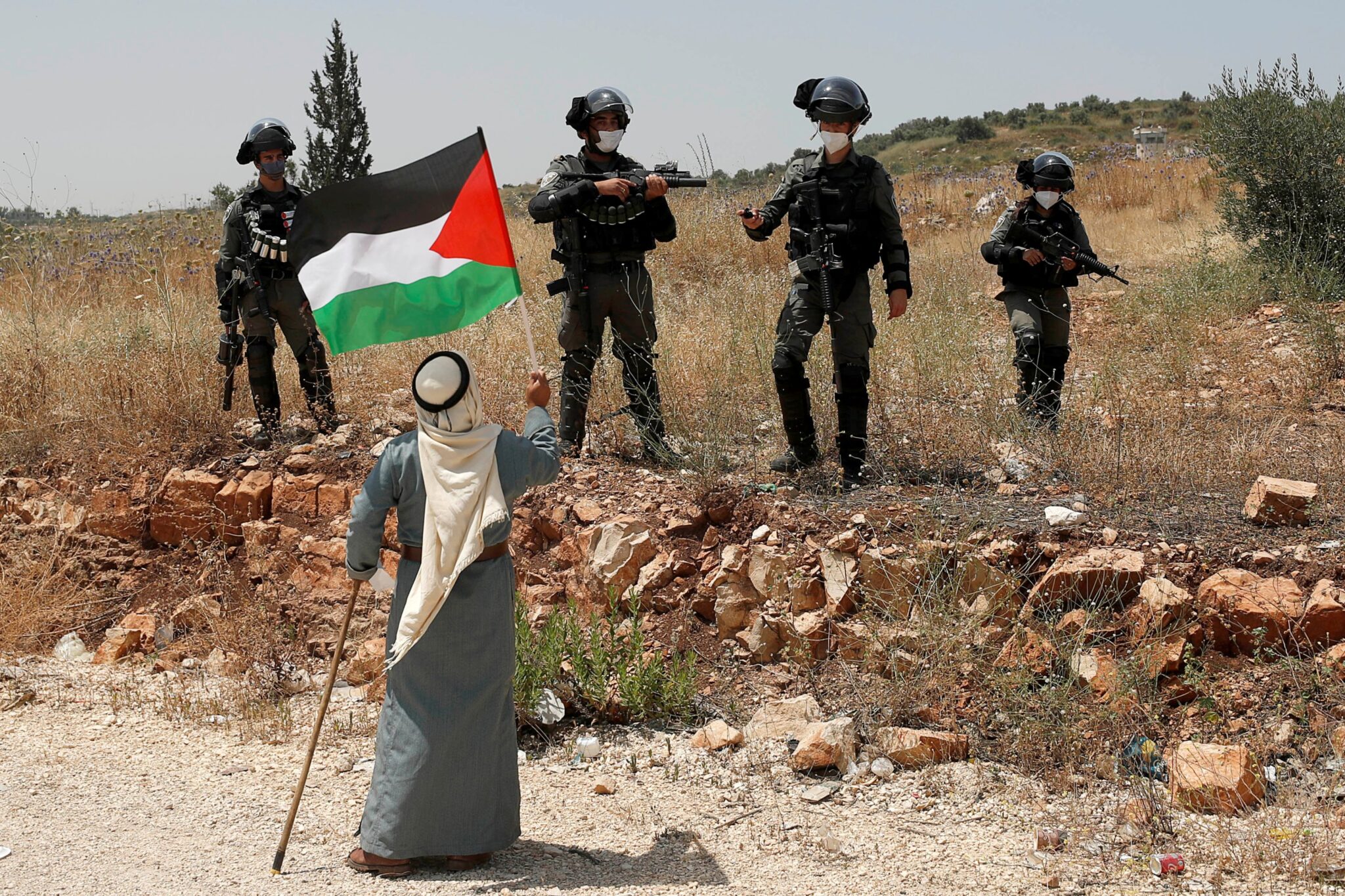 Woman waves Palestinian flag at IDF soldiers. Photo: Daily Sabah.