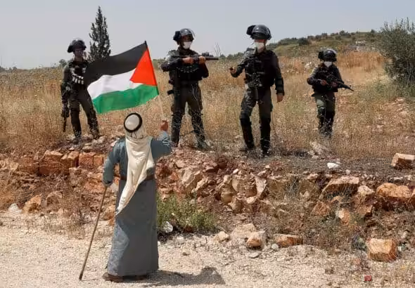 Woman waves Palestinian flag at IDF soldiers. Photo: Daily Sabah.