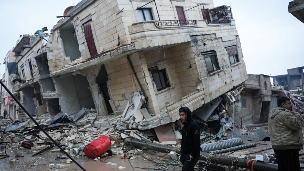 Residents stand in front of a collapsed building following an earthquake in the town of Jindires, located in the northern Syrian countryside in Afrin district, Aleppo province. Photo: Rami al Sayed/AFP via Getty Images.