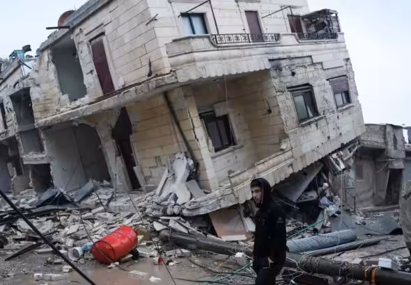 Residents stand in front of a collapsed building following an earthquake in the town of Jindires, located in the northern Syrian countryside in Afrin district, Aleppo province. Photo: Rami al Sayed/AFP via Getty Images.