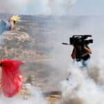 A Palestinian protester, at left, throws a tear gas canister fired by Israeli soldiers away from him as a cameraman records nearby, during a demonstration against Israel's separation barrier in the West Bank village of Bilin, near Ramallah, Friday, Sept. 11, 2009. Israel says the barrier is necessary for security while Palestinians call it a land grab. Photo: Nasser Ishtayeh/Associated Press.
