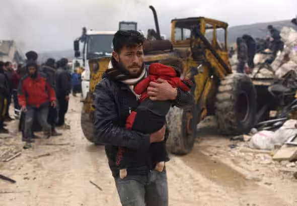 A man carries an earthquake victim in Besnia, a village near the Turkish border, Idlib province, Syria. Photo: AP/Ghaith Alsayed.