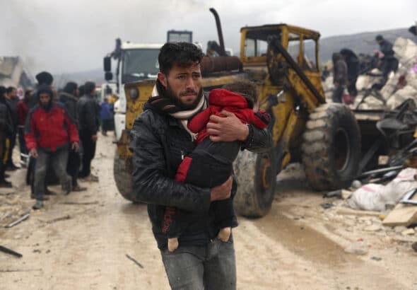 A man carries an earthquake victim in Besnia, a village near the Turkish border, Idlib province, Syria. Photo: AP/Ghaith Alsayed.