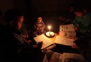A palestinian family sits inside their makeshift house during power cuts in Khan Younis in the Southern Gaza strip march 15, 2014. Photo: Ashraf Amra/APA images.