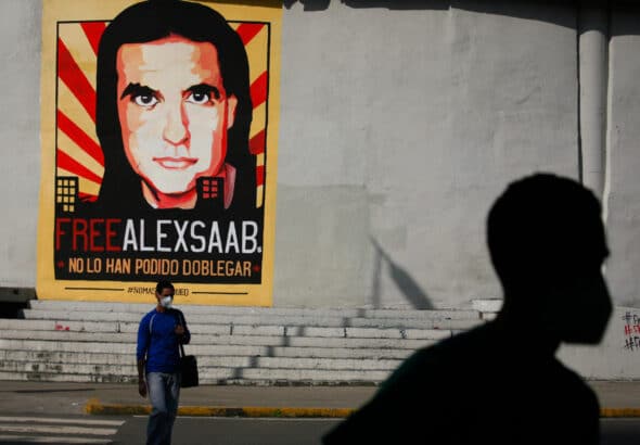 People walk past graffiti in favor of the release of Colombian businessman Alex Saab, amidst the Coronavirus pandemic, on the west side of the city in Caracas, Venezuela on September 8, 2021. Photo: Javier Campos/NurPhoto via Getty Images.