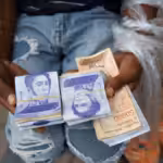 A seller holds bolívar notes and plastic bags with products. Photo: AP.