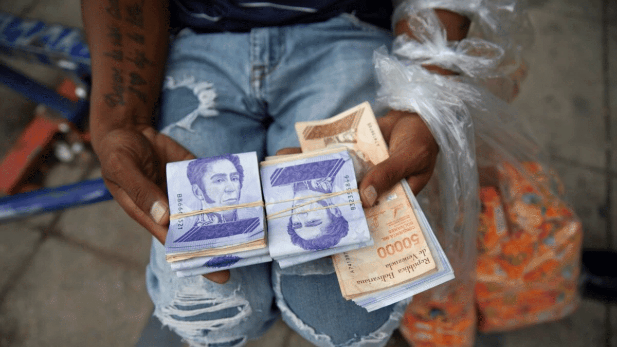 A seller holds bolívar notes and plastic bags with products. Photo: AP.
