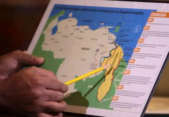 A hand holds a pencil pointing to a Venezuelan map depicting the Essequibo territory in yellow, surrounded by multiple border lines drawn by the UK, next to a timeline of the territorial dispute. Photo: File photo.