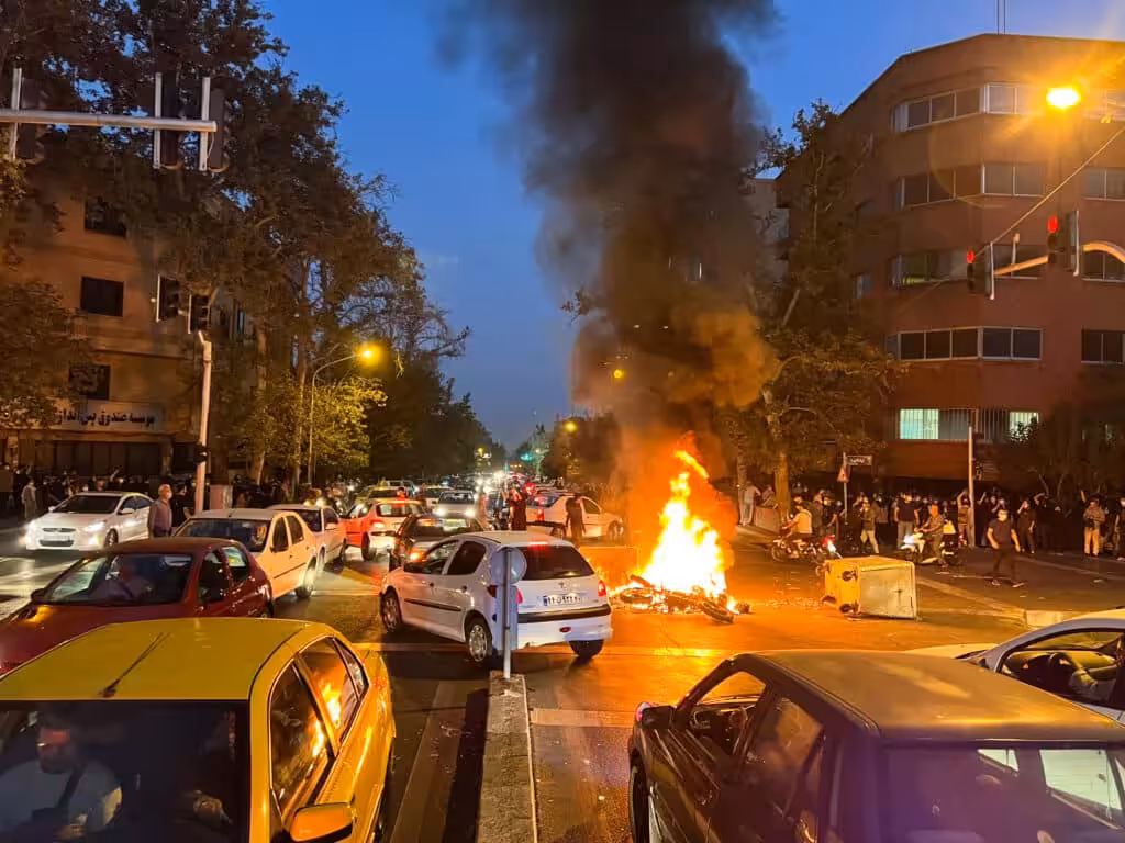 A motorcycle belonging to security forces burns in a street crowded with cars amidst 2022 riots in Tehran, Iran. Photo: West Asia News Agency.