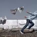 A man runs through a flurry of newspapers. File photo.