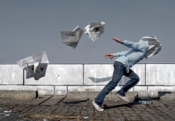 A man runs through a flurry of newspapers. File photo.