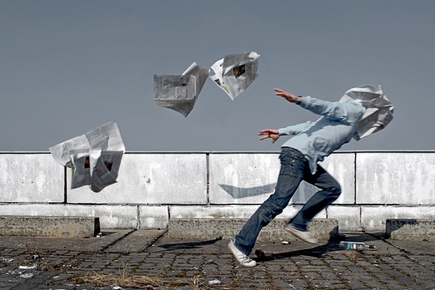 A man runs through a flurry of newspapers. File photo.