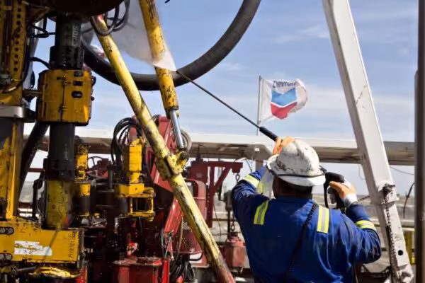 A worker maneuvering an oil rig with a Chevron flag flying in the background. Photo: File photo.