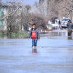 Young person wading through recent flooding in northern Syria. Photo: Getty Images.