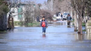 Young person wading through recent flooding in northern Syria. Photo: Getty Images.