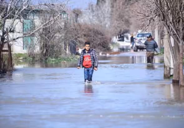 Young person wading through recent flooding in northern Syria. Photo: Getty Images.