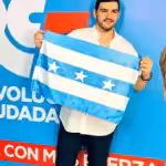 Advertisement of the Revolución Ciudadana party where a person holds a flag and in a strip at the bottom it reads : "return with more strength" and on the right side can be seen former president Rafael Correa smiling. File photo.