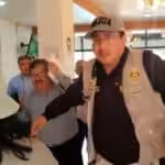 Screenshot of the video circulating on social media platforms about the incident, showing the Peruvian Vice Minister Henry Rebaza covering his face while being protected by a security agent. Photo: social media platforms, video screenshot.