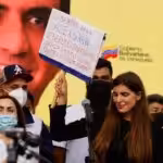 Camilla Fabri, the wife of Venezuelan diplomat Alex Saab, holds up a banner demanding freedom for the abducted diplomat. She is accompanied by supporters, with a picture of Saab's face in the background. Photo: File photo.