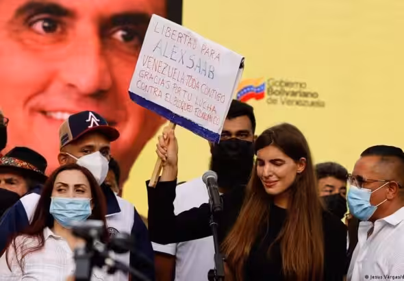 Camilla Fabri, the wife of Venezuelan diplomat Alex Saab, holds up a banner demanding freedom for the abducted diplomat. She is accompanied by supporters, with a picture of Saab's face in the background. Photo: File photo.