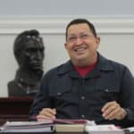 Featured image: Commander Hugo Chávez smiling while sitting in front of a statue of Simón Bolívar. Photo: Twitter/@NicolasMaduro.