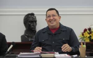 Featured image: Commander Hugo Chávez smiling while sitting in front of a statue of Simón Bolívar. Photo: Twitter/@NicolasMaduro.