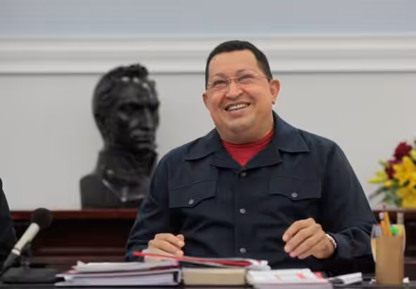 Featured image: Commander Hugo Chávez smiling while sitting in front of a statue of Simón Bolívar. Photo: Twitter/@NicolasMaduro.