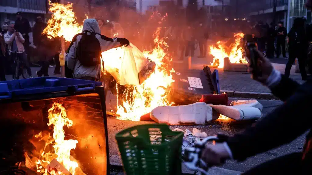 Trash cans burning in Paris, France, as protests continue in the country against the government's pension reform. Photo: AP/Jean-Francois Badias.