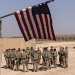 US occupation force in Syria gathered below a US flag. Photo: Getty Images.