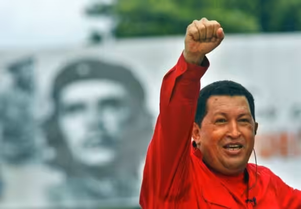 President Hugo Chavez raising his hand with a clenched fist and in the background a photo of Che. Photo: File photo.