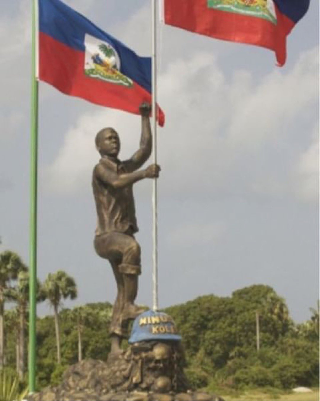 A statue in Port Salut, Haiti of a Haitian man planting the Haitian flag in a MINUSTAH helmet emblazoned with the words "MINUSTAH, Kolera."