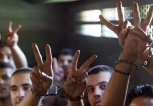 Handcuffed Palestinian prisoners show the victory sign. File photo.