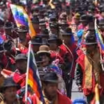 Organizers on the ground in red panchos and with the wiphala flag. Photo: Kawsachun News.