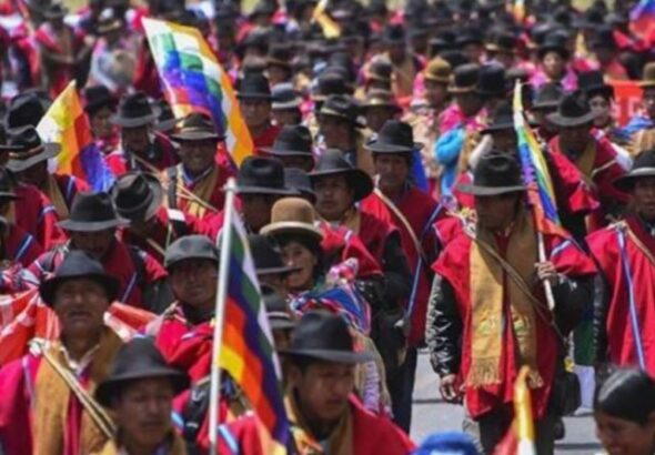 Organizers on the ground in red panchos and with the wiphala flag. Photo: Kawsachun News.
