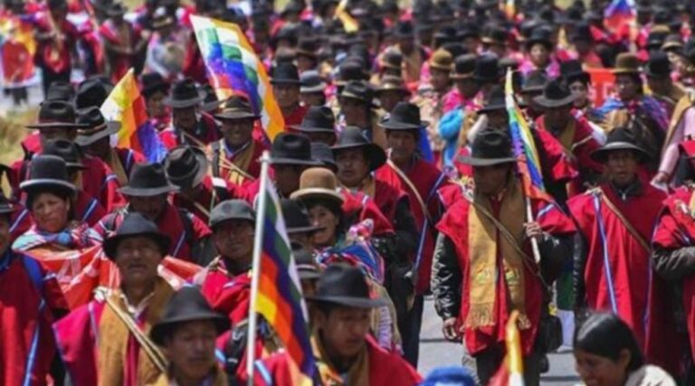 Organizers on the ground in red panchos and with the wiphala flag. Photo: Kawsachun News.
