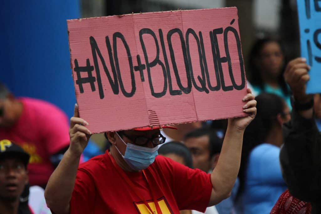 Venezuelan woman holding a banner that reads "#No+Bloqueó" (#No+Blockade) during a public Anti-Imperialism Day event in Plaza Bolívar in Caracas, condemning the eighth anniversary of the signing of the US Executive Order declaring Venezuela an "Unusual and Extraordinary Threat" to US security. Thursday, March 9, 2023. Photo: Fausto Torrealba/Últimas Noticias.