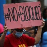 Venezuelan woman holding a banner that reads "#No+Bloqueó" (#No+Blockade) during a public Anti-Imperialism Day event in Plaza Bolívar in Caracas, condemning the eighth anniversary of the signing of the US Executive Order declaring Venezuela an "Unusual and Extraordinary Threat" to US security. Thursday, March 9, 2023. Photo: Fausto Torrealba/Últimas Noticias.