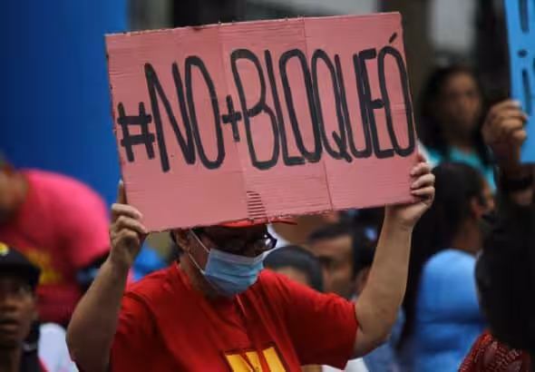 Venezuelan woman holding a banner that reads "#No+Bloqueó" (#No+Blockade) during a public Anti-Imperialism Day event in Plaza Bolívar in Caracas, condemning the eighth anniversary of the signing of the US Executive Order declaring Venezuela an "Unusual and Extraordinary Threat" to US security. Thursday, March 9, 2023. Photo: Fausto Torrealba/Últimas Noticias.