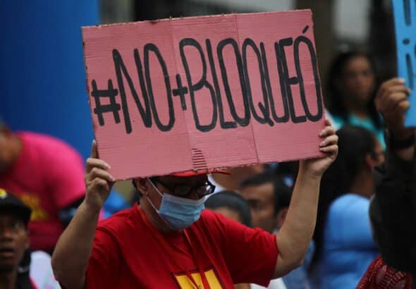 Venezuelan woman holding a banner that reads "#No+Bloqueó" (#No+Blockade) during a public Anti-Imperialism Day event in Plaza Bolívar in Caracas, condemning the eighth anniversary of the signing of the US Executive Order declaring Venezuela an "Unusual and Extraordinary Threat" to US security. Thursday, March 9, 2023. Photo: Fausto Torrealba/Últimas Noticias.